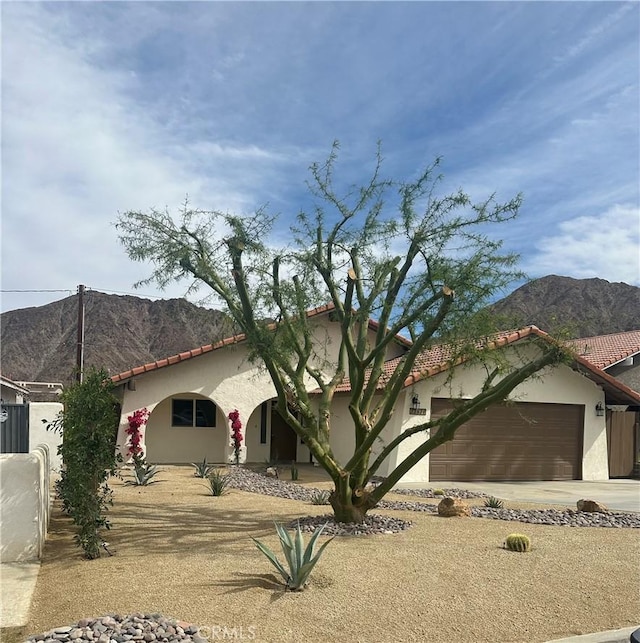 mediterranean / spanish-style house with stucco siding, covered porch, a mountain view, a garage, and driveway