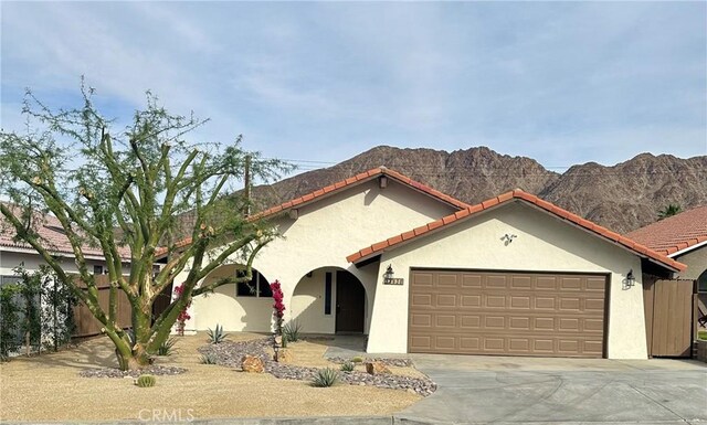 mediterranean / spanish-style house featuring driveway, a tiled roof, an attached garage, a mountain view, and stucco siding