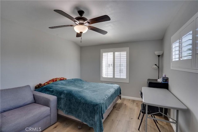 bedroom featuring light wood finished floors, a ceiling fan, and baseboards