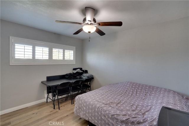 bedroom with ceiling fan, wood finished floors, and baseboards