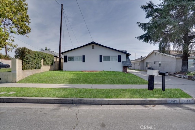 view of front of home with a front yard, fence, driveway, and stucco siding