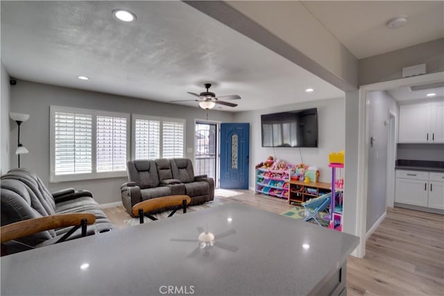 living area with light wood-type flooring, ceiling fan, baseboards, and recessed lighting