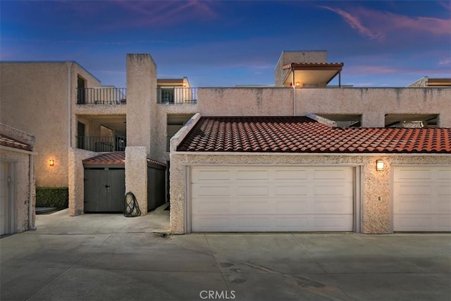 townhome / multi-family property featuring a garage, a tiled roof, and stucco siding