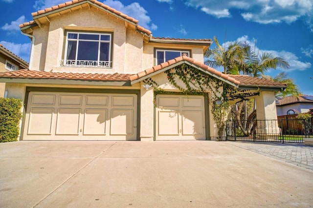 mediterranean / spanish home featuring concrete driveway, a tiled roof, an attached garage, fence, and stucco siding