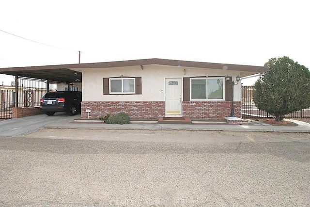 manufactured / mobile home featuring an attached carport, brick siding, fence, and stucco siding