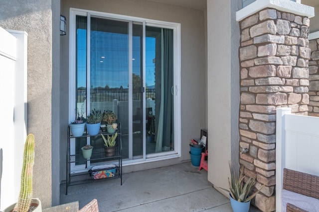 doorway to property featuring stone siding and stucco siding