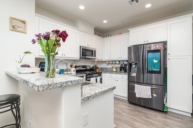 kitchen with stainless steel appliances, a peninsula, visible vents, and white cabinetry