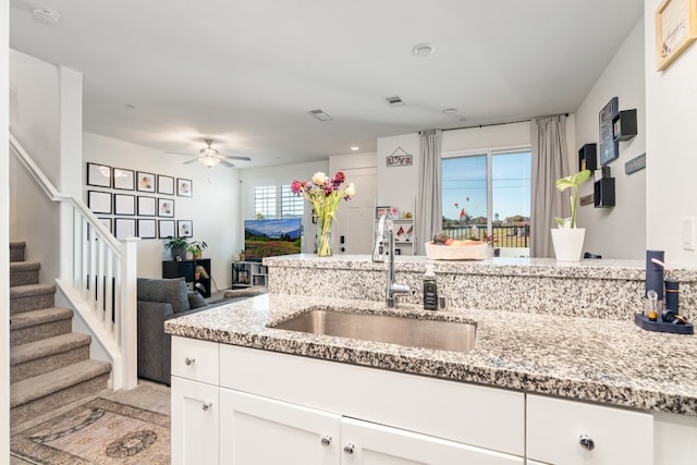 kitchen featuring white cabinetry, a sink, visible vents, and light stone countertops