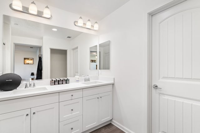 bathroom with double vanity, visible vents, baseboards, and a sink