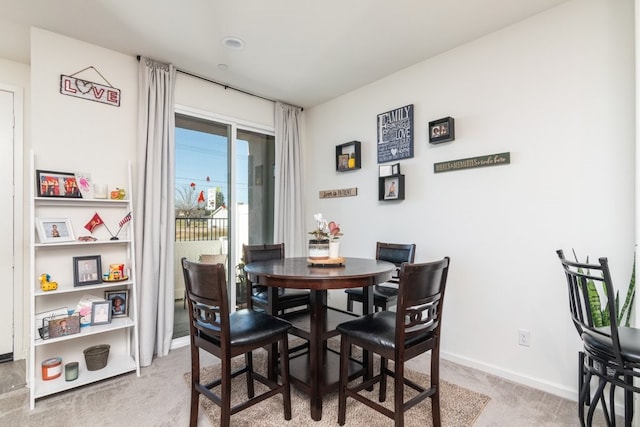 dining room featuring light colored carpet and baseboards