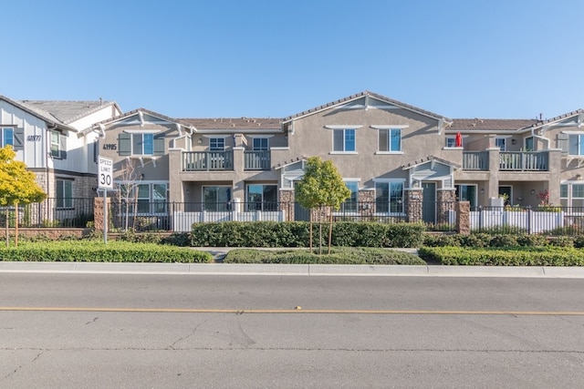 townhome / multi-family property featuring a residential view, fence, and stucco siding