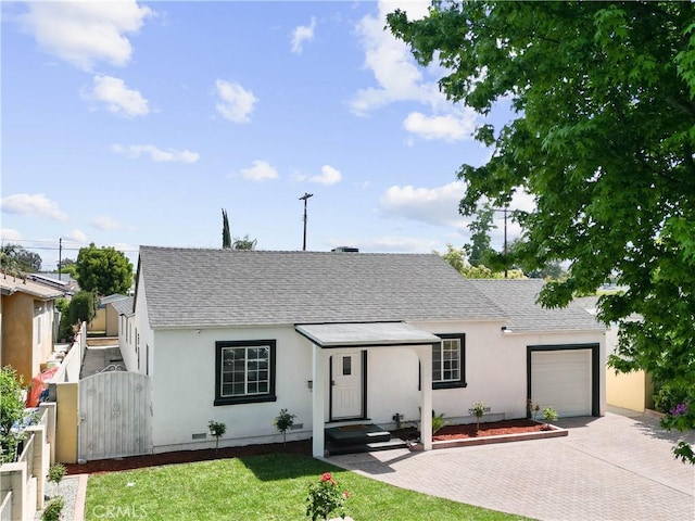 single story home featuring a garage, a shingled roof, a gate, fence, and decorative driveway