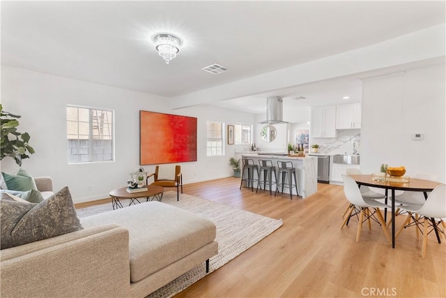 living area featuring light wood-style floors, baseboards, and visible vents