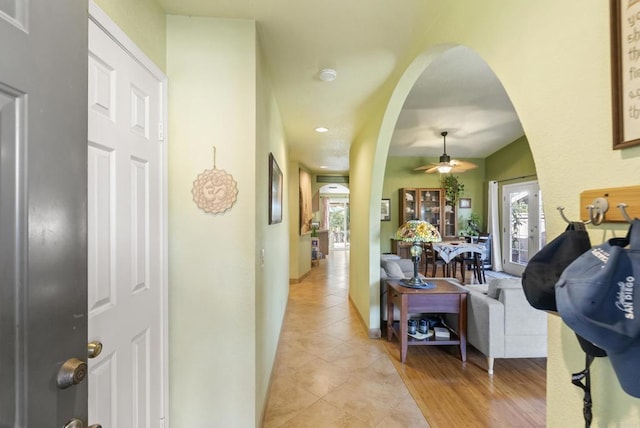 hallway with arched walkways, light tile patterned flooring, and recessed lighting