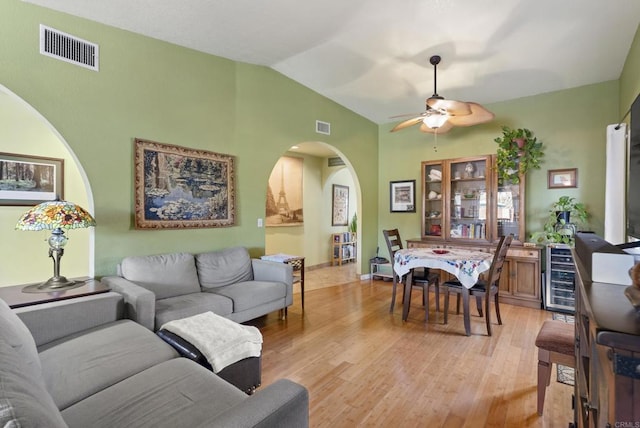 living room with light wood-type flooring, ceiling fan, visible vents, and lofted ceiling