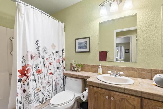 bathroom with a shower with curtain, a textured wall, vanity, and toilet