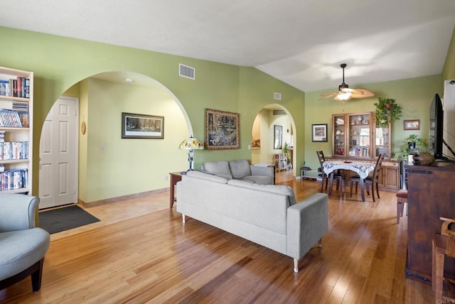 living room featuring lofted ceiling, visible vents, a ceiling fan, light wood-type flooring, and baseboards