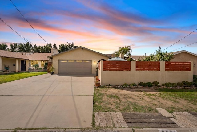 view of front of property with a garage, fence, driveway, and stucco siding