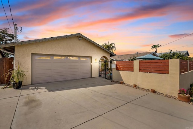 garage with concrete driveway, fence, and a gate