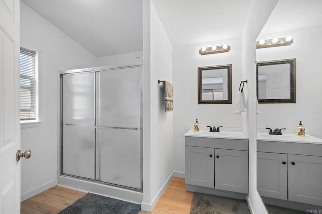 bathroom featuring a shower stall, two vanities, a sink, and wood finished floors