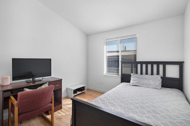 bedroom featuring vaulted ceiling, light wood finished floors, and baseboards