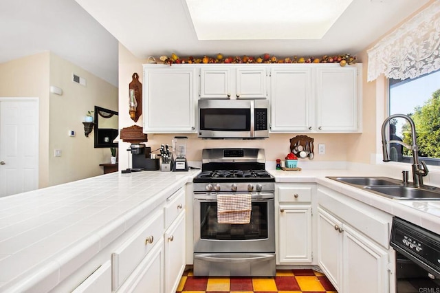 kitchen featuring stainless steel appliances, visible vents, a sink, and tile countertops