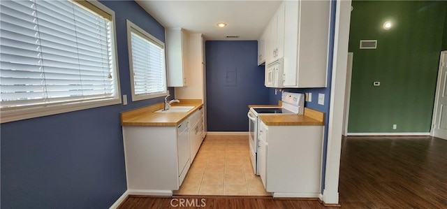 kitchen featuring white appliances, visible vents, white cabinets, light countertops, and a sink