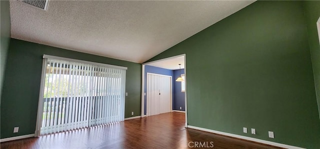 unfurnished room featuring visible vents, vaulted ceiling, baseboards, and wood finished floors