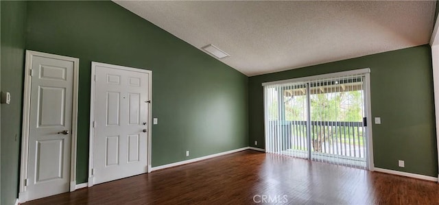 empty room with a textured ceiling, baseboards, vaulted ceiling, and wood finished floors