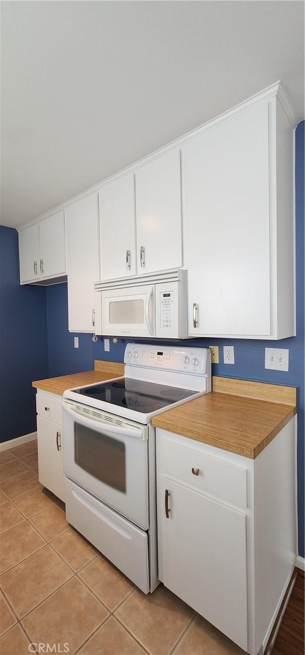 kitchen featuring light tile patterned floors, light countertops, white appliances, and white cabinetry