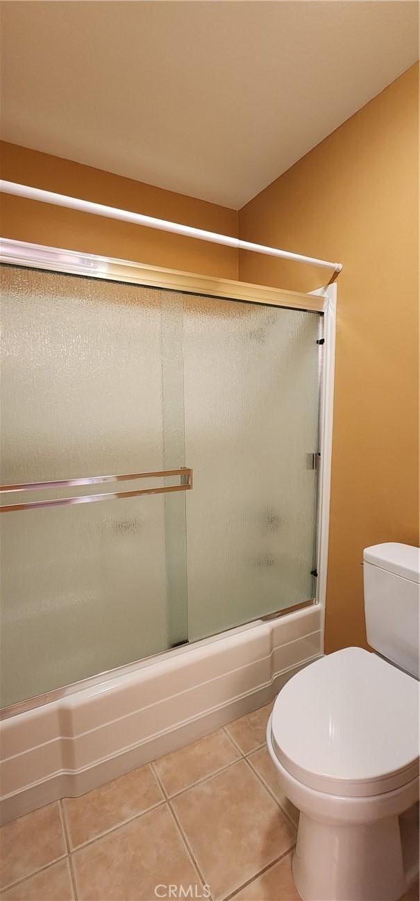 full bathroom featuring toilet, enclosed tub / shower combo, and tile patterned floors