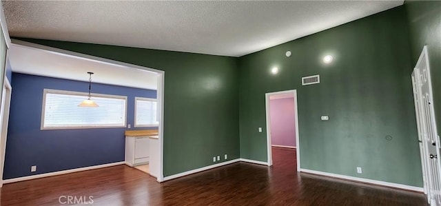 empty room with baseboards, a textured ceiling, visible vents, and wood finished floors