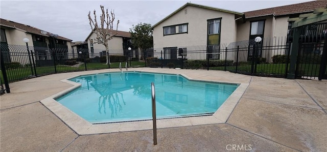 community pool with a patio area and fence