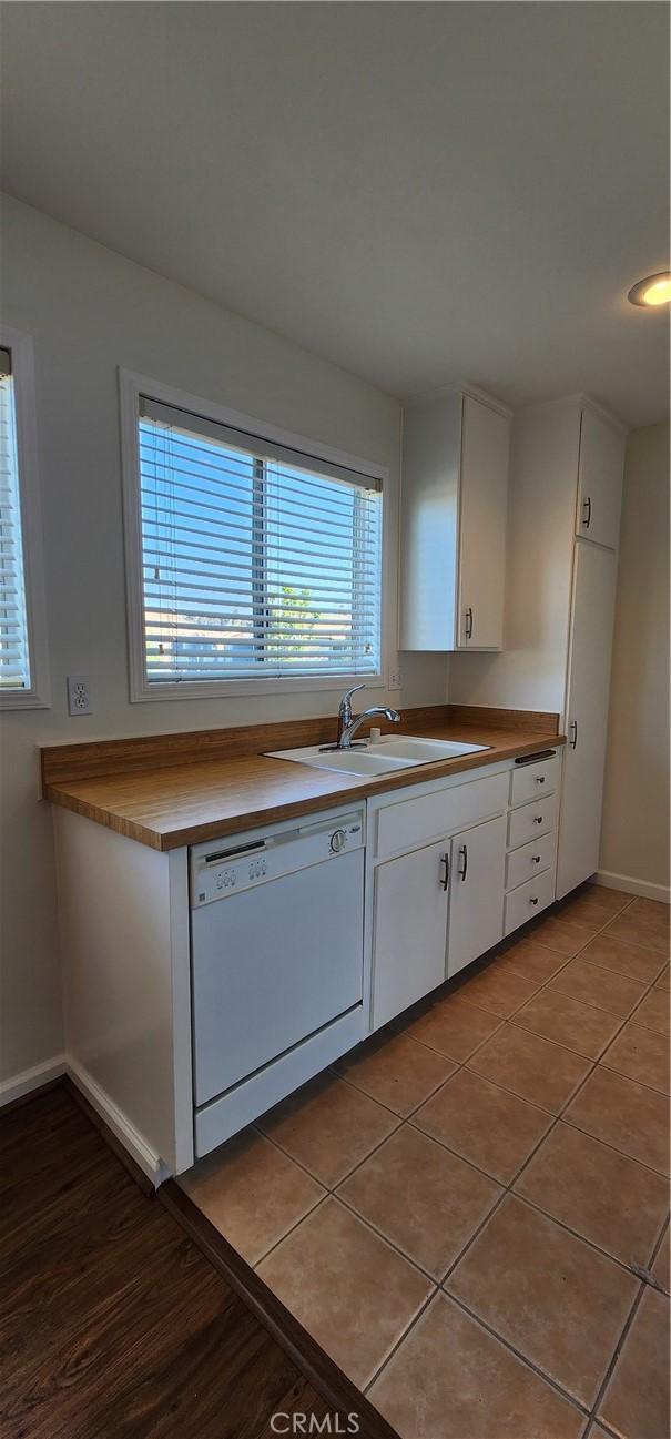 23230 Orange Ave Unit 2, Lake Forest, CA 92630 - kitchen featuring dishwasher, a sink, white cabinetry, baseboards, and light tile patterned flooring