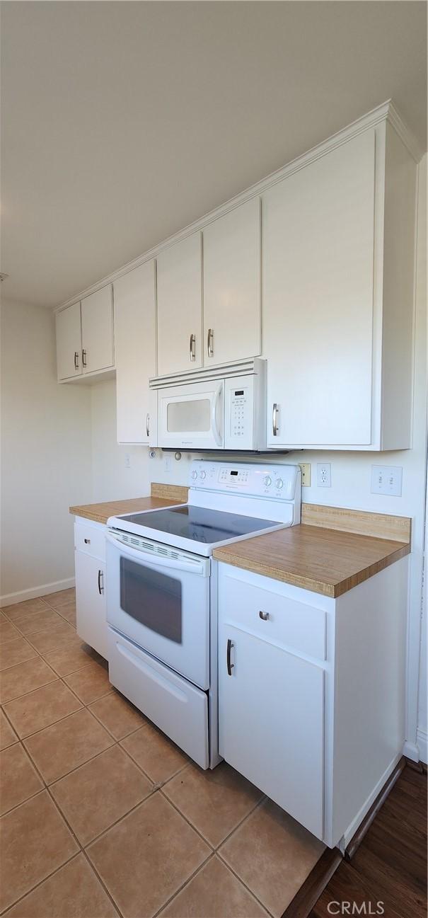 23230 Orange Ave Unit 2, Lake Forest, CA 92630 - kitchen with white appliances, white cabinetry, baseboards, and light tile patterned floors