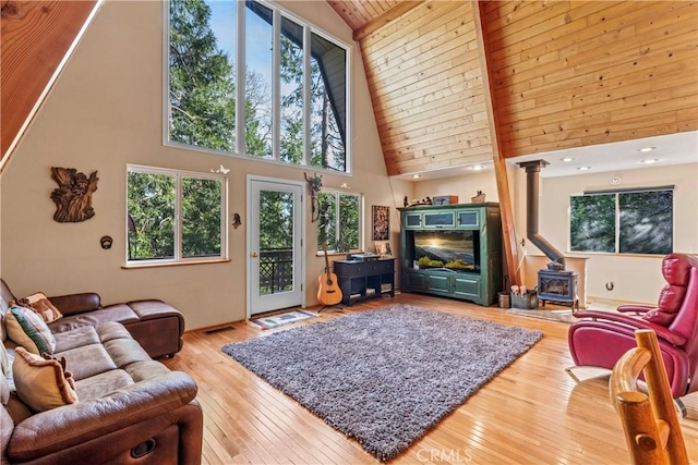 living room with a wood stove, wooden ceiling, high vaulted ceiling, and hardwood / wood-style floors