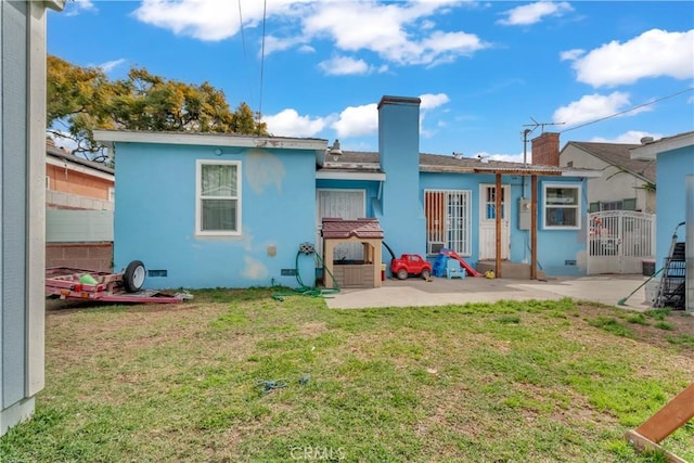 back of house with crawl space, stucco siding, a lawn, and a patio