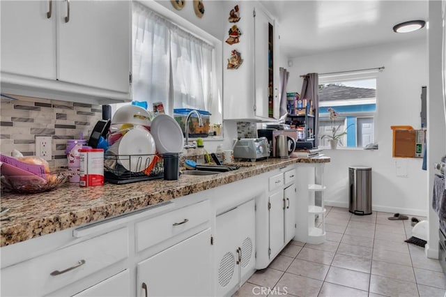 kitchen featuring a sink, light tile patterned flooring, backsplash, and white cabinetry