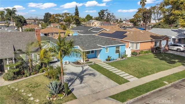 ranch-style home featuring concrete driveway, roof with shingles, a front yard, and a residential view