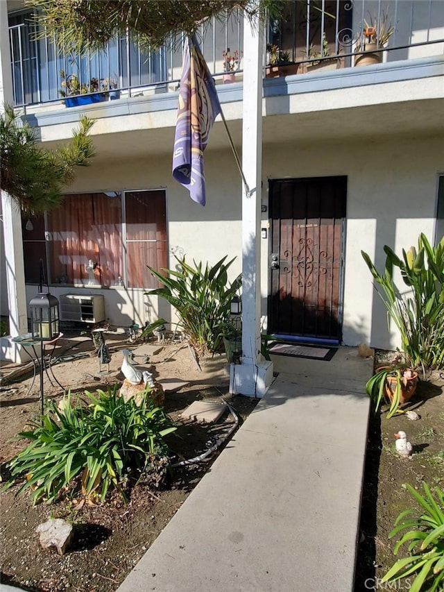 view of exterior entry featuring a balcony and stucco siding