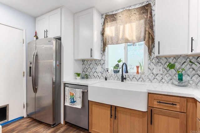 kitchen featuring wood finished floors, a sink, stainless steel appliances, light countertops, and backsplash