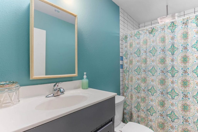 bathroom with toilet, a textured wall, vanity, and a shower with curtain