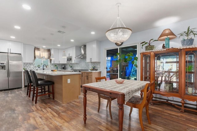 kitchen featuring stainless steel appliances, wall chimney exhaust hood, a sink, and backsplash