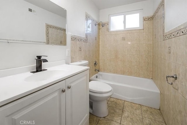 bathroom featuring visible vents, toilet, tile patterned floors, vanity, and tile walls