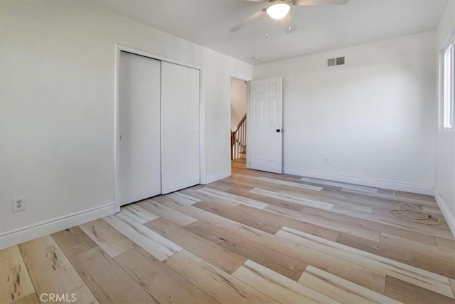 unfurnished bedroom featuring baseboards, visible vents, ceiling fan, light wood-style floors, and a closet