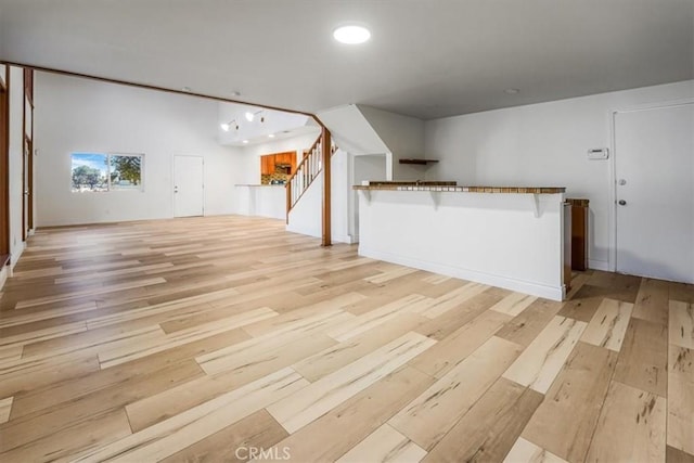 unfurnished living room with light wood-style flooring and stairway