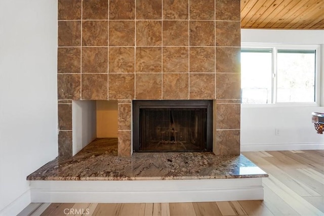 interior details featuring a tile fireplace, baseboards, and wood finished floors