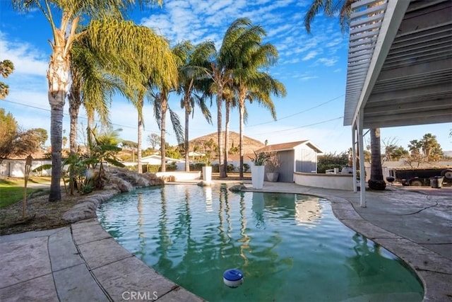 view of swimming pool featuring a patio area, a storage unit, and an outdoor structure