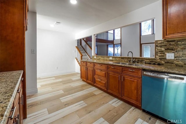 kitchen with light wood finished floors, dishwasher, light stone counters, backsplash, and a sink