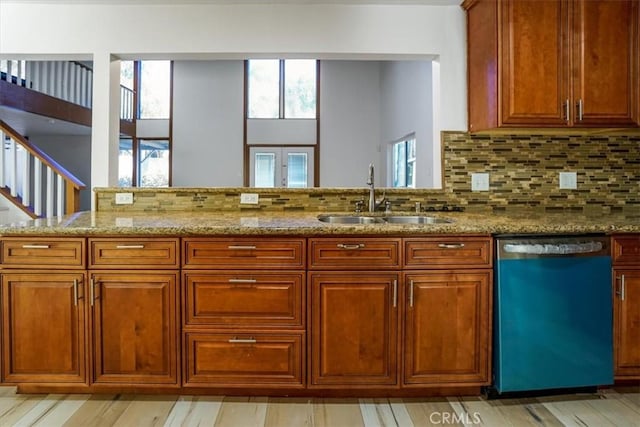 kitchen featuring tasteful backsplash, brown cabinetry, a sink, light stone countertops, and dishwasher